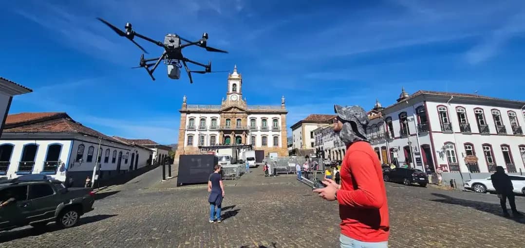 Da sala de aula ao campo: profissionais da Mi2 Geotecnologias operam um drone em uma praça histórica cercada por construções coloniais durante atividade de campo