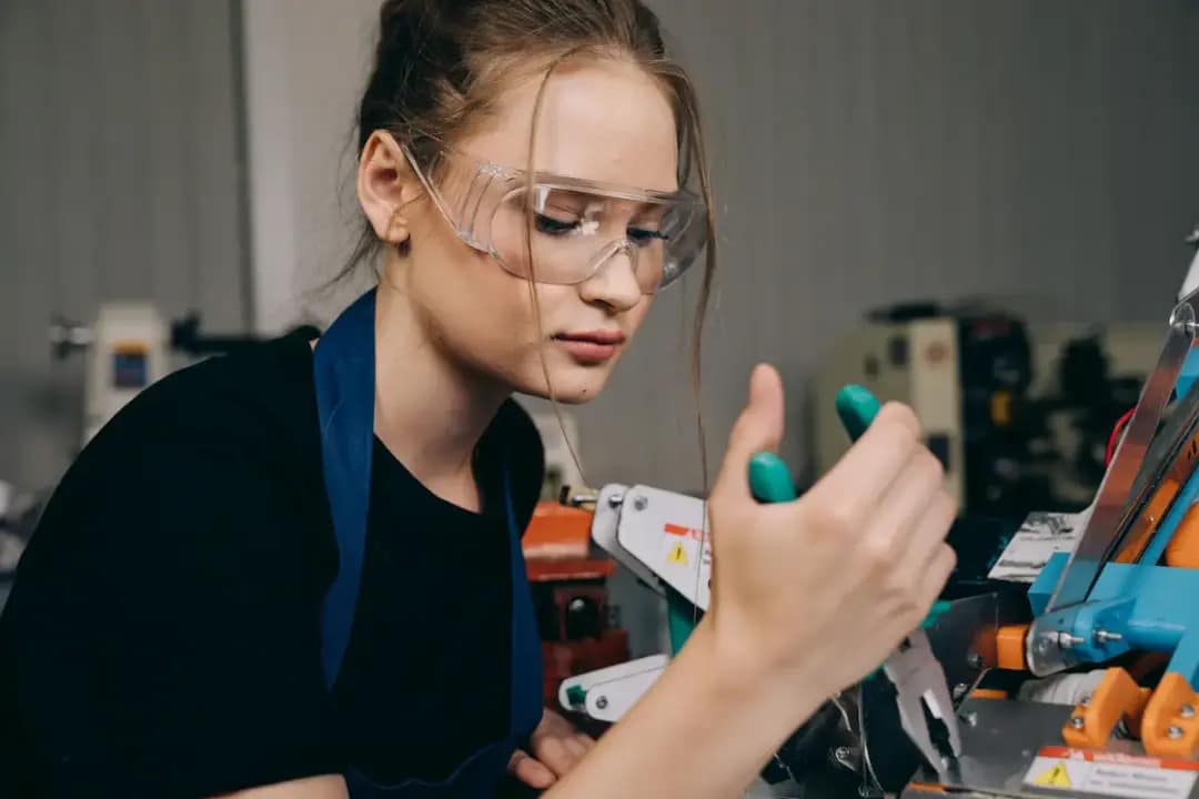 Jovem aprendiz utiliza equipamento industrial com óculos de proteção durante atividade prática em ambiente de formação profissional do Senais MG