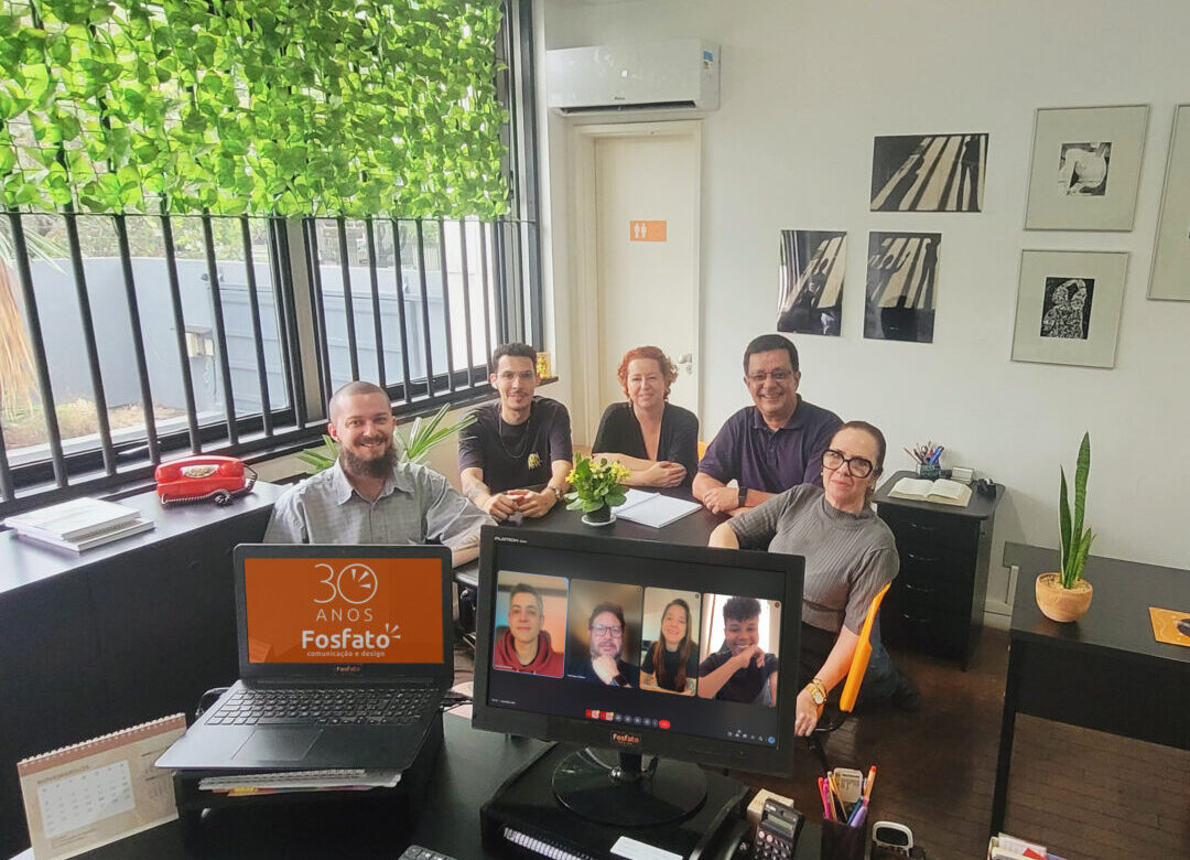 Equipe da Fosfato Comunicação reunida na sede em Belo Horizonte, com parte do time presencial e parte em reunião virtual