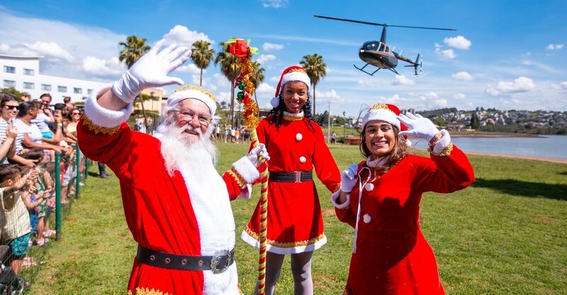 Papai Noel e ajudantes acenam para o público em evento natalino da CSul Lagoa dos Ingleses