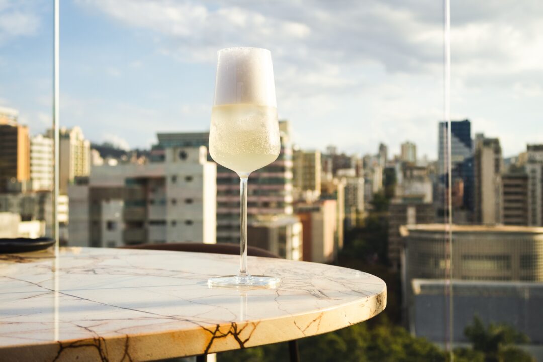 Taça de espumante em destaque com vista panorâmica da Praça da Liberdade durante a celebração de Réveillon em Belo Horizonte
