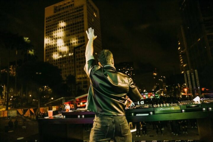 Música eletrônica ganha espaço no Carnaval de BH com o Bloco da Mokaii DJ Luan Poffo se apresenta em palco ao ar livre durante evento de música eletrônica no Carnaval, com público reunido em espaço urbano iluminado à noite
