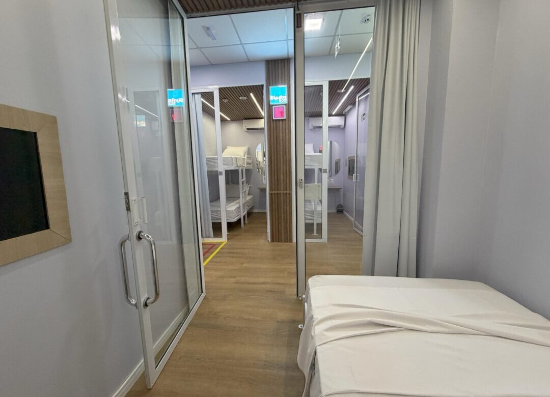 Interior de uma cabine de descanso no BH Airport, equipada com cama, iluminação suave e estrutura para relaxamento do passageiro