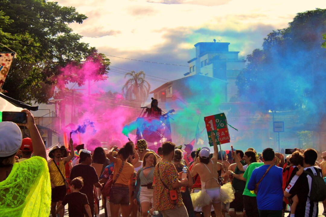 Cortejo de Carnaval em Santa Tereza, BH, com público e fumaça colorida durante desfile do Maria Baderna