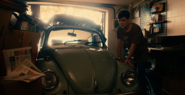 Filme O Velho Fusca estreia nos cinemas brasileiros Cena do filme O Velho Fusca mostra jovem ao lado de carro antigo em garagem