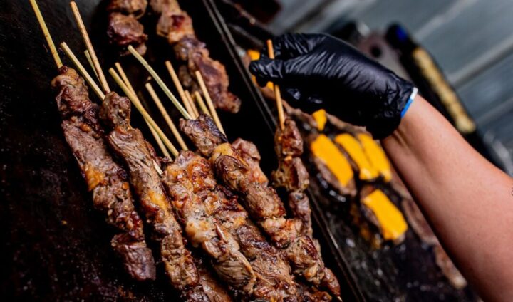 Festival Butequeiros reúne pratos típicos da culinária mineira em BH Espetinhos de carne sendo preparados na chapa durante festival gastronômico em Belo Horizonte; outra atração junto com estreia de Michael