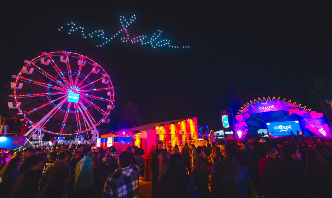 Público na Cidade Junina em Belo Horizonte com roda-gigante iluminada e palco de shows ao fundo