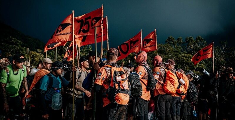 Integrantes do movimento Legendários participam de jornada ao ar livre com mochilas, bandeiras e atividades coletivas durante experiência de desenvolvimento humano e espiritualidade