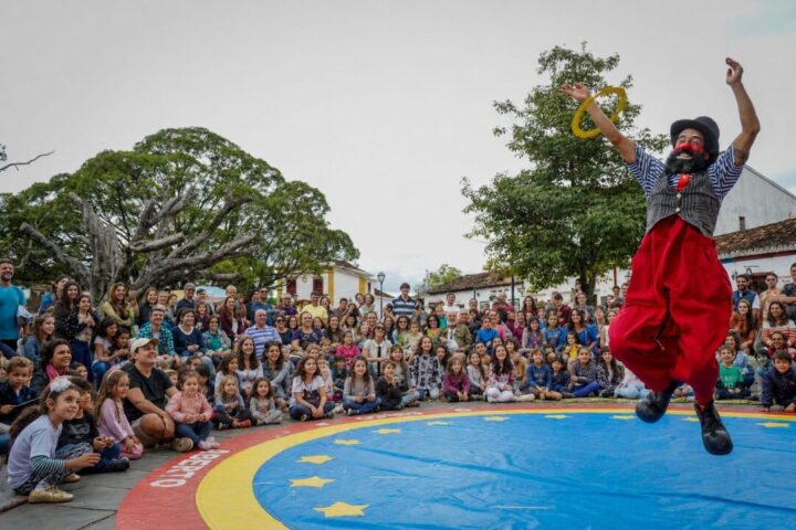 Mostra Tiradentes em Cena ocupa ruas históricas com teatro, circo e performances Palhaço se apresenta ao ar livre diante de crianças e famílias durante espetáculo circense na Mostra Tiradentes em Cena, em praça pública da cidade histórica de Tiradentes