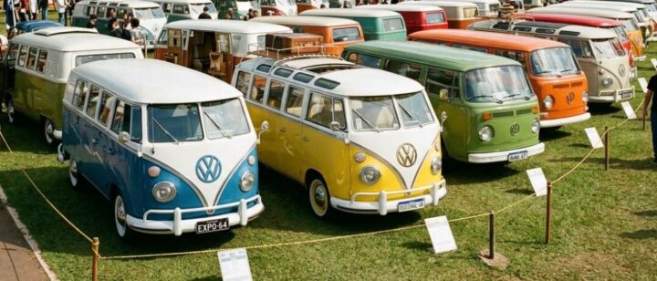 Encontro de Kombis reúne clássicos da Volkswagen no Portal Auto Shopping em BH Diversas Kombis antigas da Volkswagen, em cores variadas como azul, amarelo, verde e laranja, aparecem expostas em gramado durante evento automotivo ao ar livre com presença de visitantes