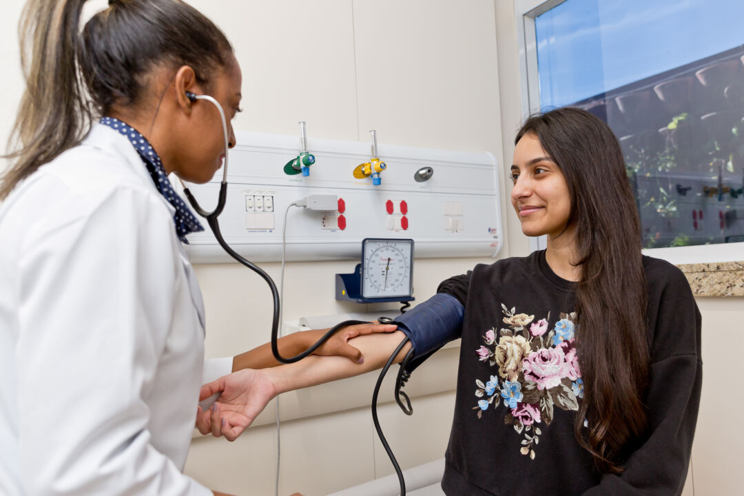 Profissional de saúde aferindo pressão arterial de paciente durante exame de prevenção à hipertensão