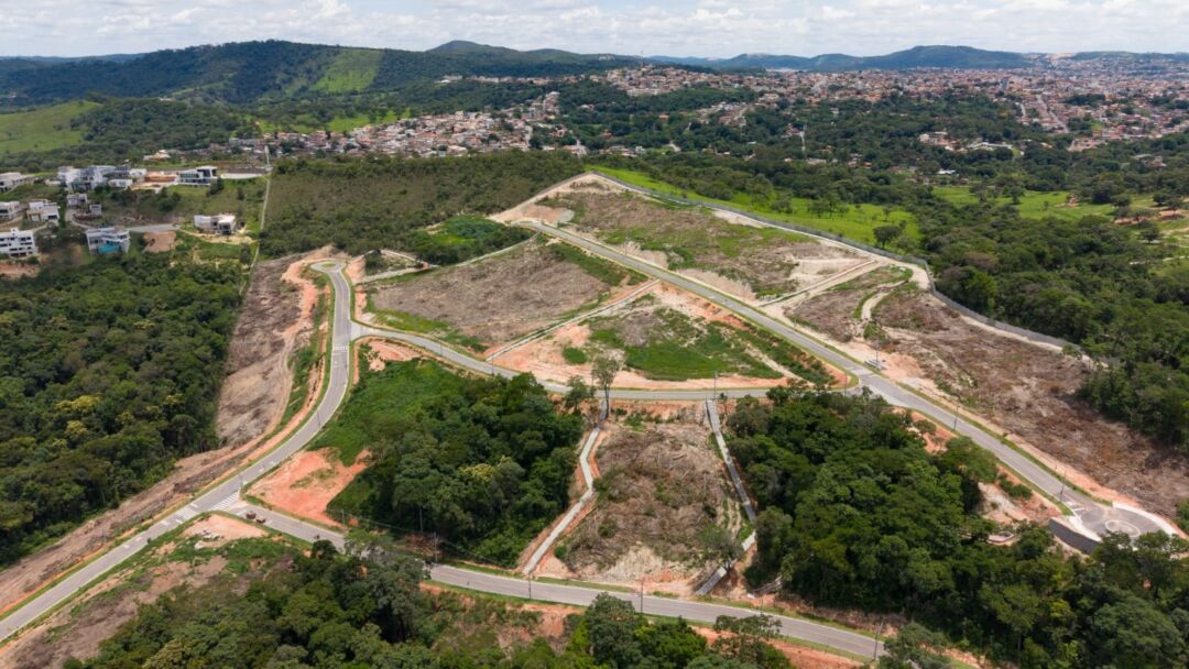 Vista aérea do condomínio Reserva da Mata, em Betim, com lotes liberados, vias internas e extensa área verde preservada ao redor do empreendimento.