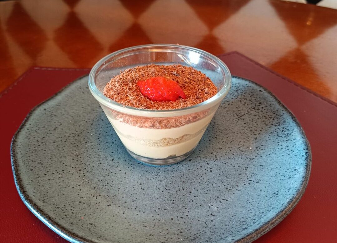 Sobremesa servida durante a BH Restaurant Week em Belo Horizonte, com creme em camadas, raspas de chocolate e morango, apresentada em prato escuro