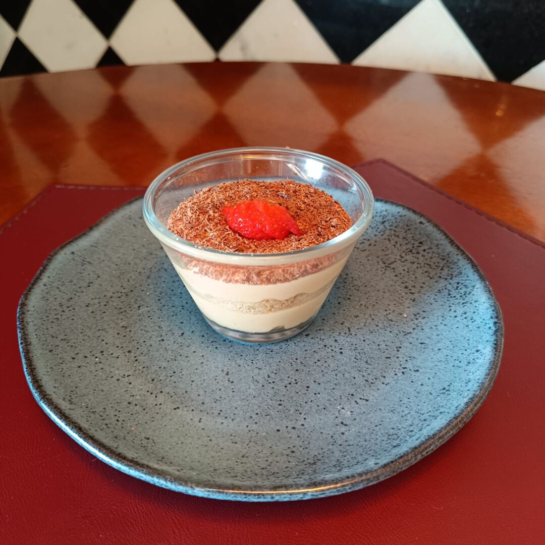 Sobremesa da BH Restaurant Week em Belo Horizonte Sobremesa servida durante a BH Restaurant Week em Belo Horizonte, com creme em camadas, raspas de chocolate e morango, apresentada em prato escuro