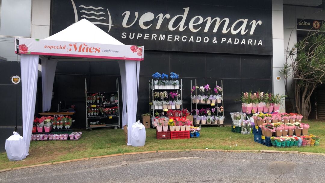 Estrutura de drive-thru com flores montada na entrada do Verdemar em Belo Horizonte durante campanha de Dia das Mães