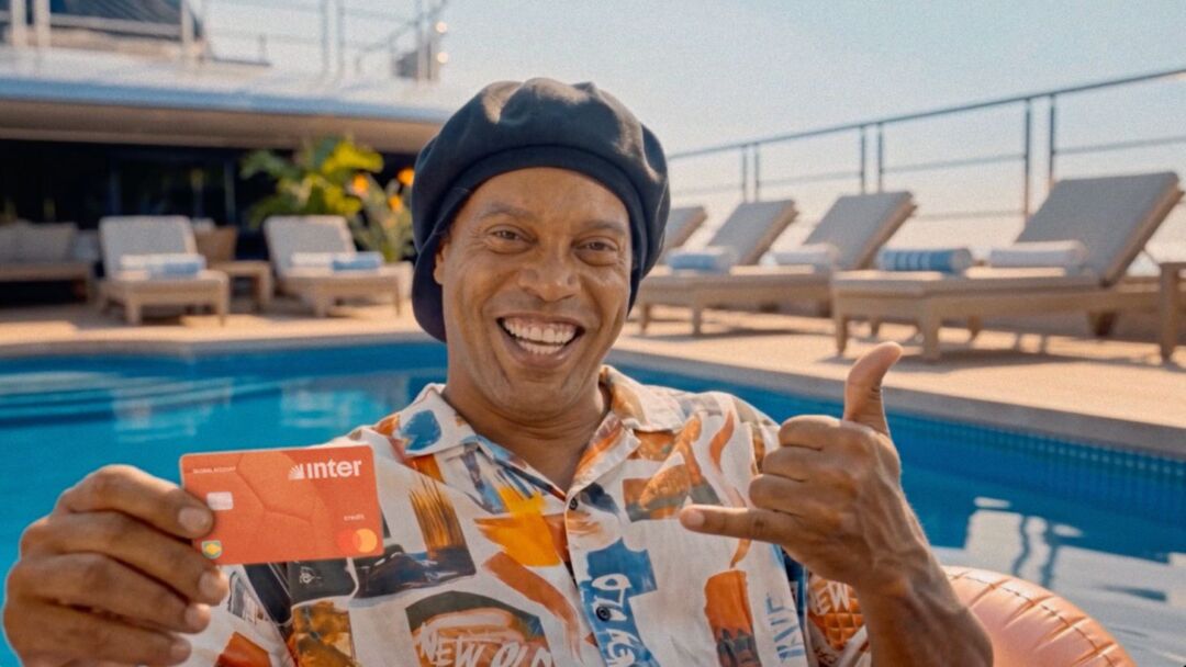 Ronaldinho Gaúcho segura cartão do Inter durante campanha “Rolê Aleatório” voltada à Global Account do banco
