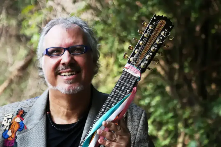 Violeiro Chico Lobo segura instrumento de cordas durante ensaio fotográfico em área arborizada