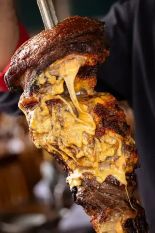 Porcão BH reúne churrasco e presentes para o Dia dos Pais Corte de carne assada na brasa com queijo derretido no Porcão BH