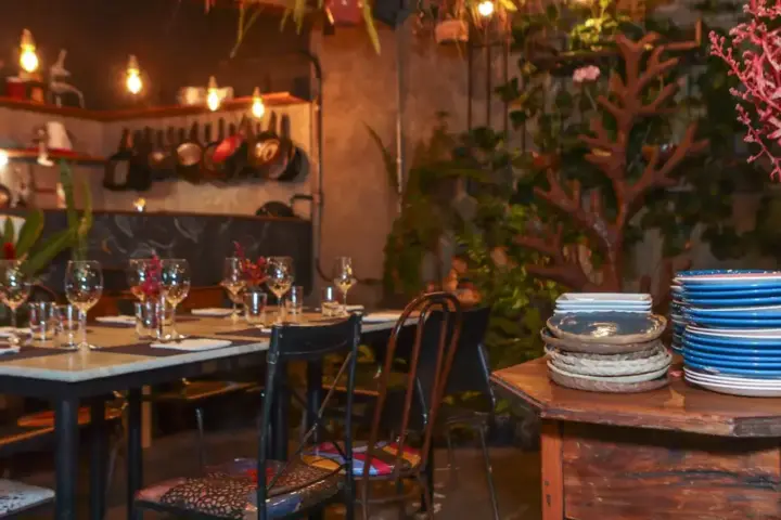 Bistrô no Quintal com Chefs Créditos Carina Medina Ambiente do bistrô Quintal com Chefs, na Savassi, em Belo Horizonte, com mesas decoradas e área interna do restaurante
