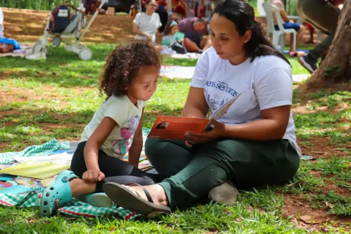 Mãe e criança participam de piquenique literário ao ar livre durante a Feira Encantaria em Belo Horizonte