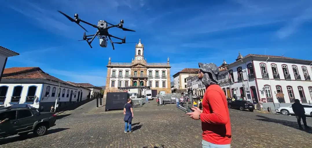Da sala de aula ao campo: profissionais da Mi2 Geotecnologias operam um drone em uma praça histórica cercada por construções coloniais durante atividade de campo