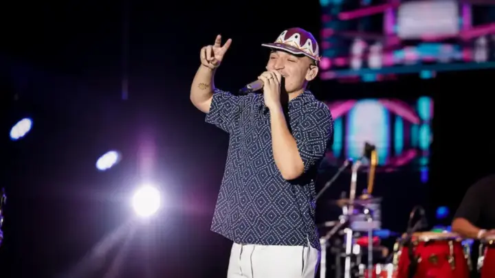 Cantor João Gomes se apresenta ao microfone em um palco iluminado durante show
