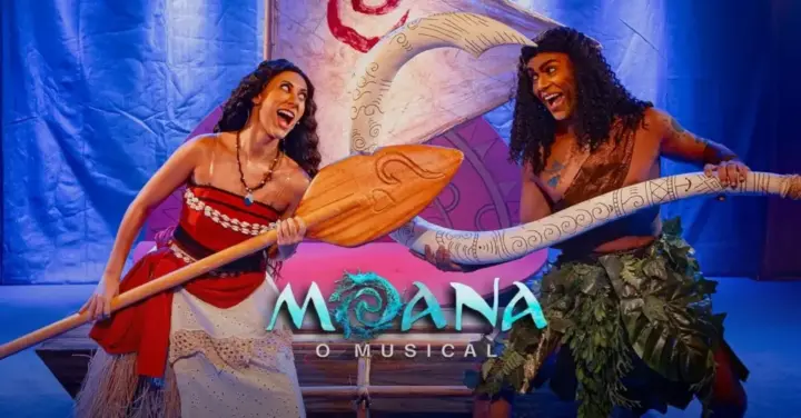 Atores caracterizados como Moana e Maui seguram remos durante cena do espetáculo Moana: O Musical, com cenário inspirado na animação - Comédia