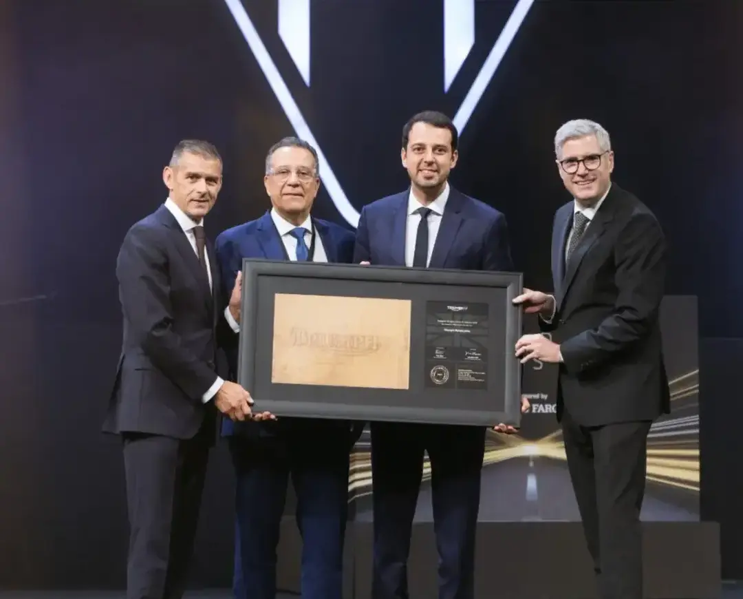 Triumph BHR conquista prêmio global da Triumph Motorcycles Representantes da Triumph BHR posam em um palco durante uma cerimônia de premiação, segurando juntos um quadro comemorativo