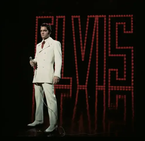 Elvis Presley vestido com terno branco durante apresentação musical, em imagem histórica que integra o espetáculo Elvis in Concert Live on Screen, em Belo Horizonte
